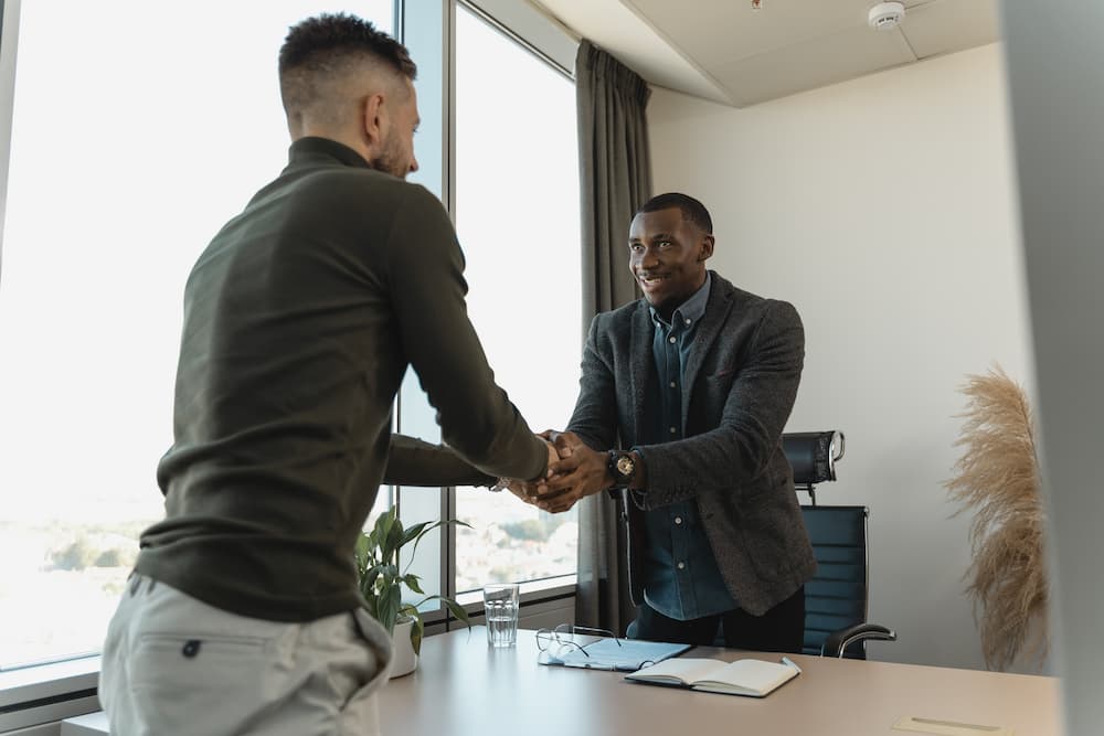 Image of two man doing a handshake in an office.